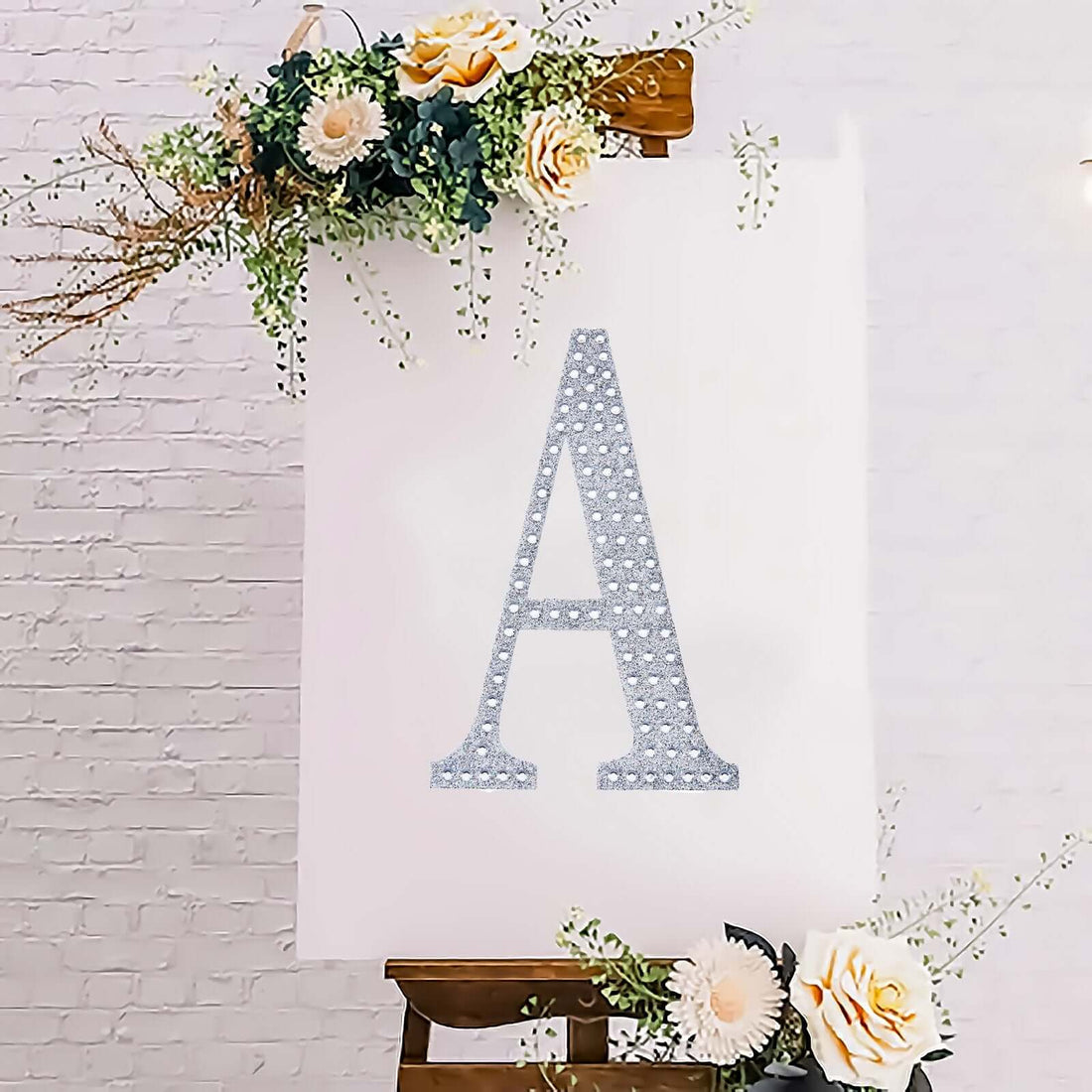 Decorative letter A displayed on an easel surrounded by flowers.