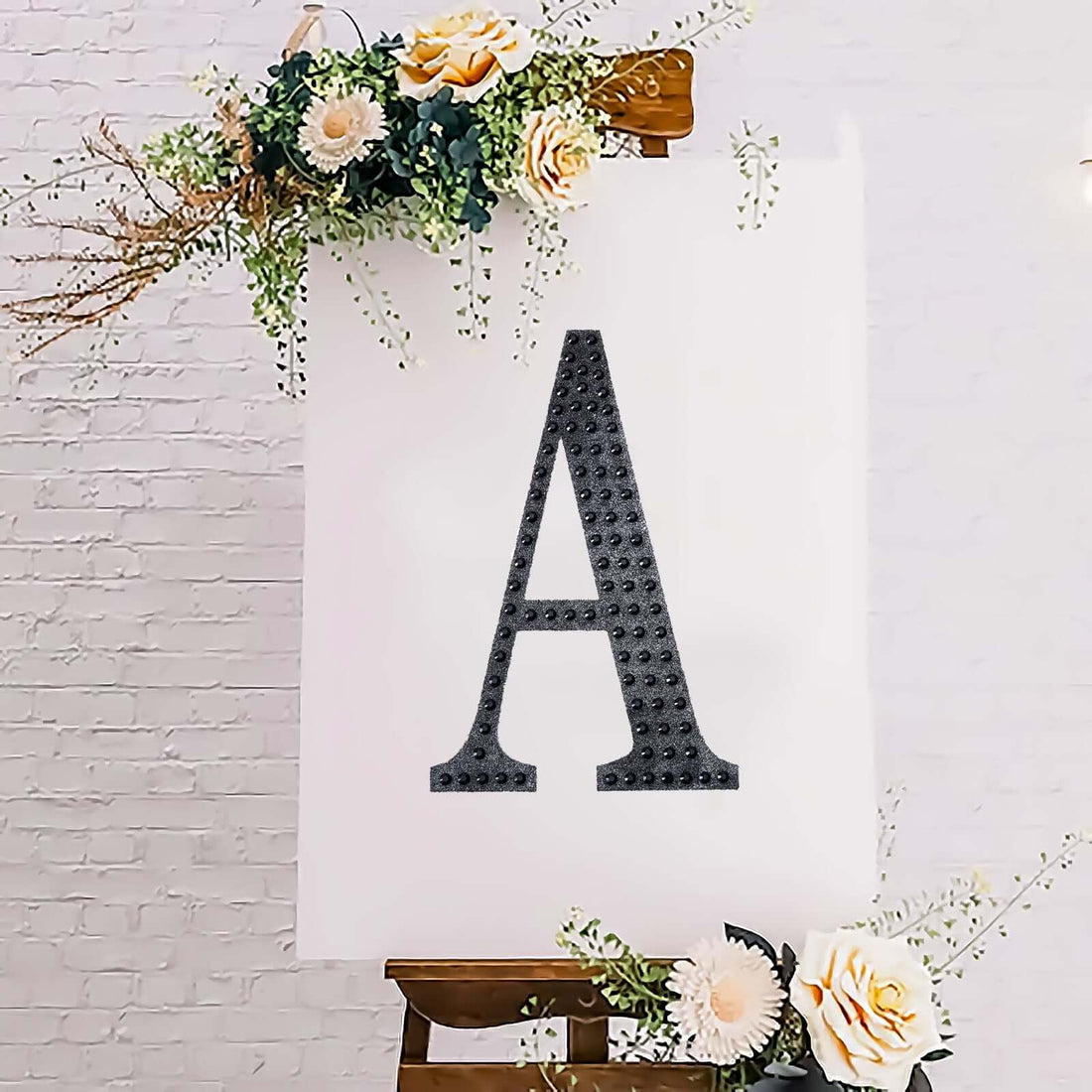 Black letter "A" displayed on an easel with floral decorations.