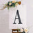 Black letter "A" displayed on an easel with floral decorations.