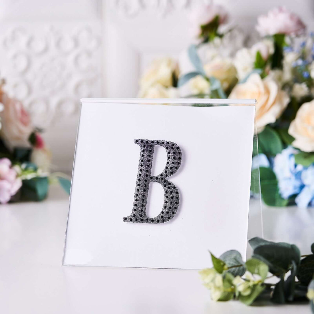 Decorative letter "B" with rhinestones on a clear display stand.