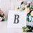 Decorative letter "B" with rhinestones on a clear display stand.