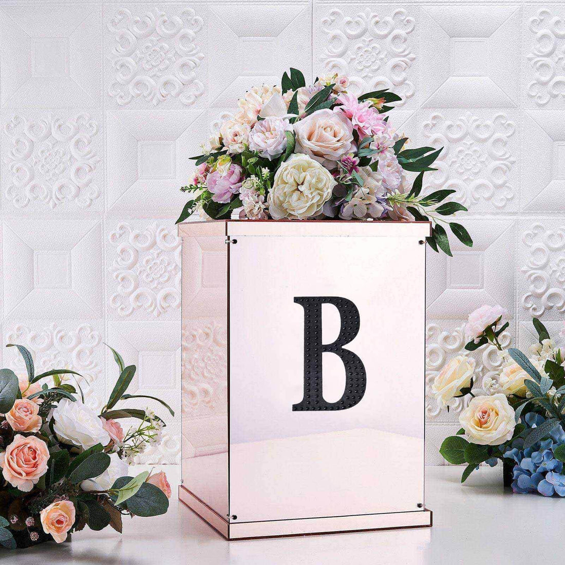 Floral arrangement in a decorative box with a letter "B" on it.