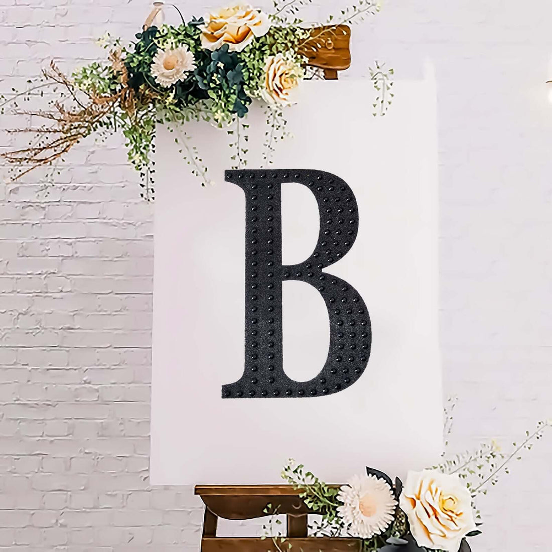 Decorative letter "B" on an easel with floral accents.