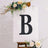 Decorative letter "B" on an easel with floral accents.