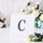 Decorative letter "C" with rhinestones on a clear display stand.