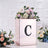 Elegant floral arrangement in a mirrored box with letter "C" on a textured backdrop.