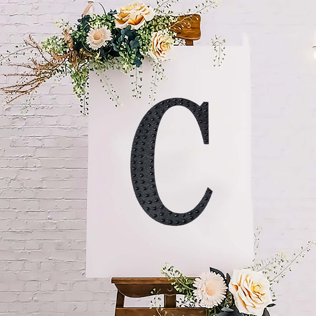 Decorative letter "C" on an easel with flowers, ideal for events or celebrations.