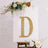 Decorative letter "D" with lights on an easel, adorned with flowers.