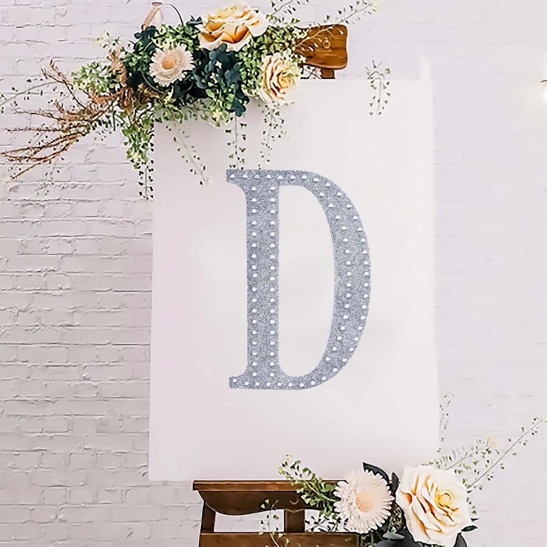 Decorative letter "D" adorned with flowers on an easel.