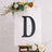 Decorative letter "D" on an easel with floral accents.