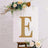 Glittery gold letter "E" on a decorative display with flowers.