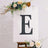 Decorative letter "E" on an easel with floral accents.