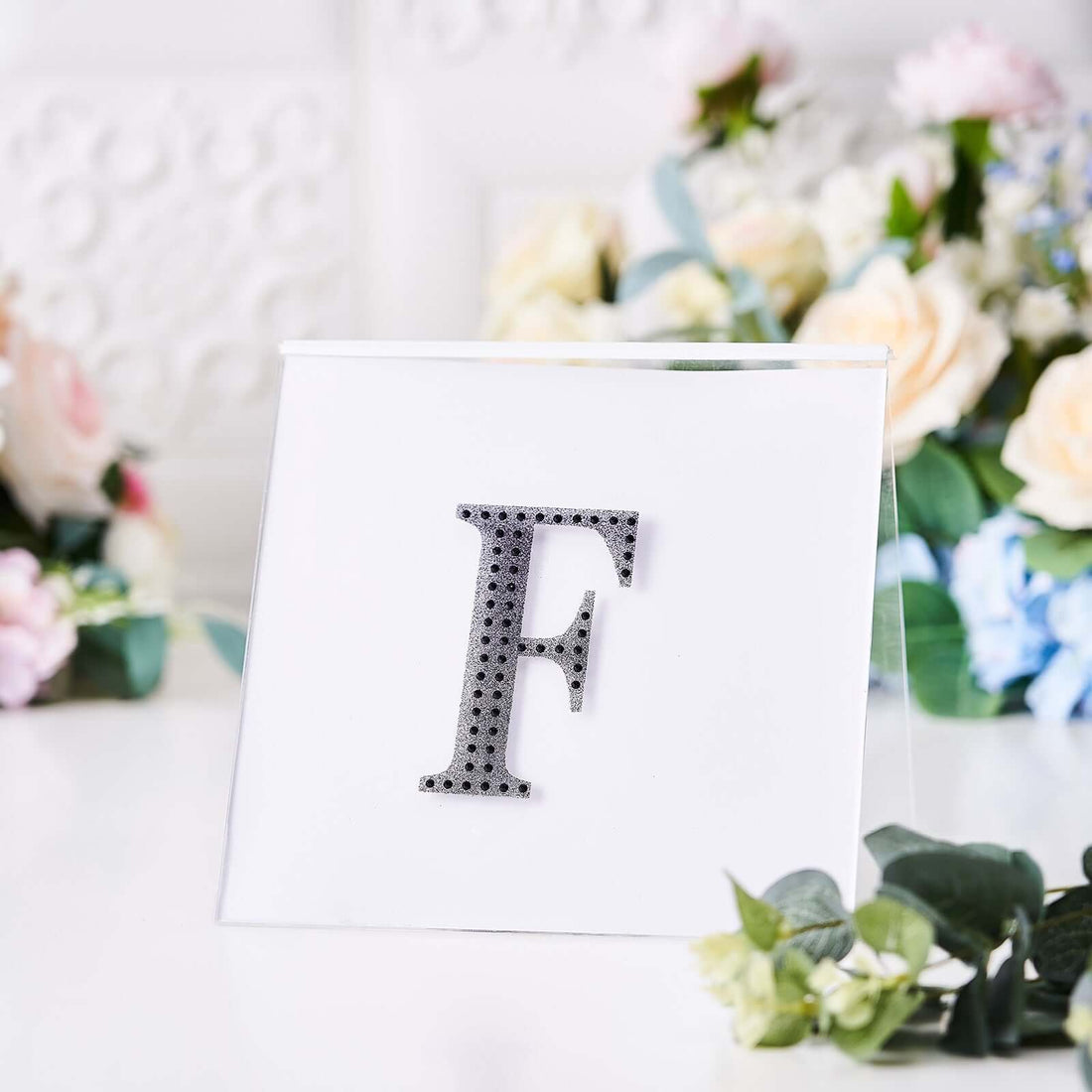 Rhinestone letter F in a clear display with floral background.
