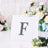 Rhinestone letter F in a clear display with floral background.