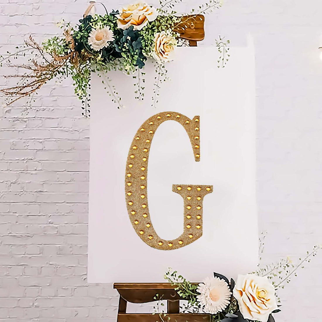 Decorative gold letter "G" on a white canvas with floral accents.