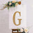 Decorative gold letter "G" on a white canvas with floral accents.