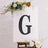 Decorative letter "G" displayed on an easel with floral accents.