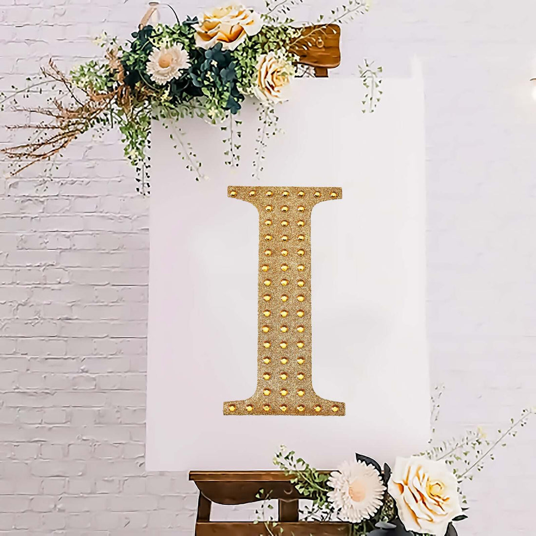 Gold rhinestone letter "I" on a white backdrop with floral accents.