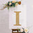 Gold rhinestone letter "I" on a white backdrop with floral accents.