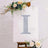 Decorative letter "I" with glitter on a floral backdrop.