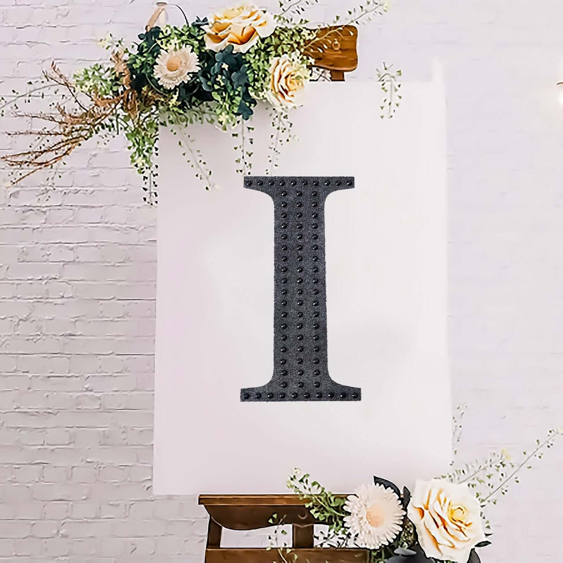 Decorative letter "I" displayed on an easel with flowers