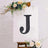 Decorative letter "J" on an easel with floral accents.