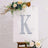 Glittery letter K displayed on an easel with floral accents.