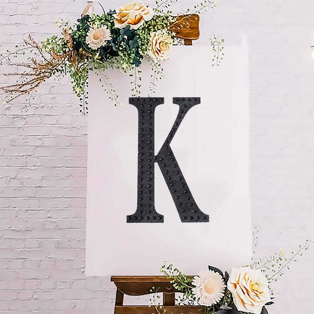 Decorative letter "K" displayed on an easel with floral accents.