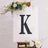 Decorative letter "K" displayed on an easel with floral accents.