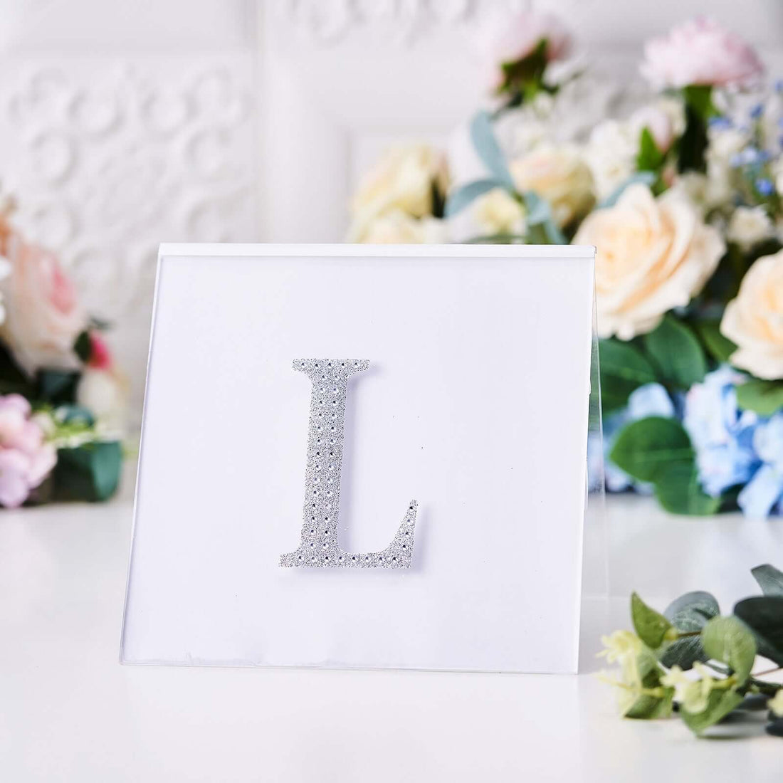 Silver rhinestone letter "L" on a clear acrylic display.