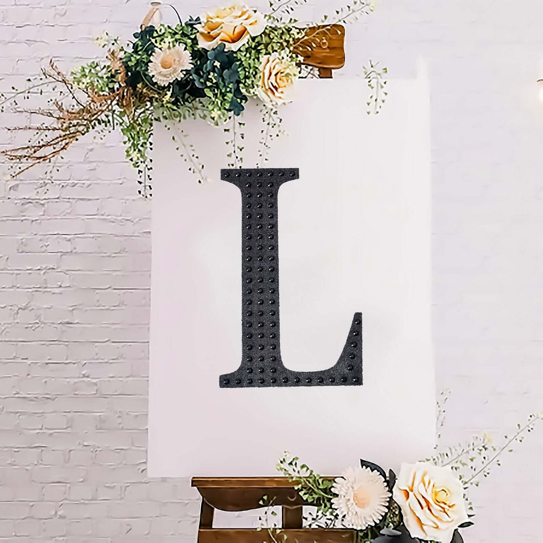 Decorative letter "L" on a white canvas with floral accents.
