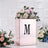 Rose gold flower box with floral arrangement and letter "M" on a white background.