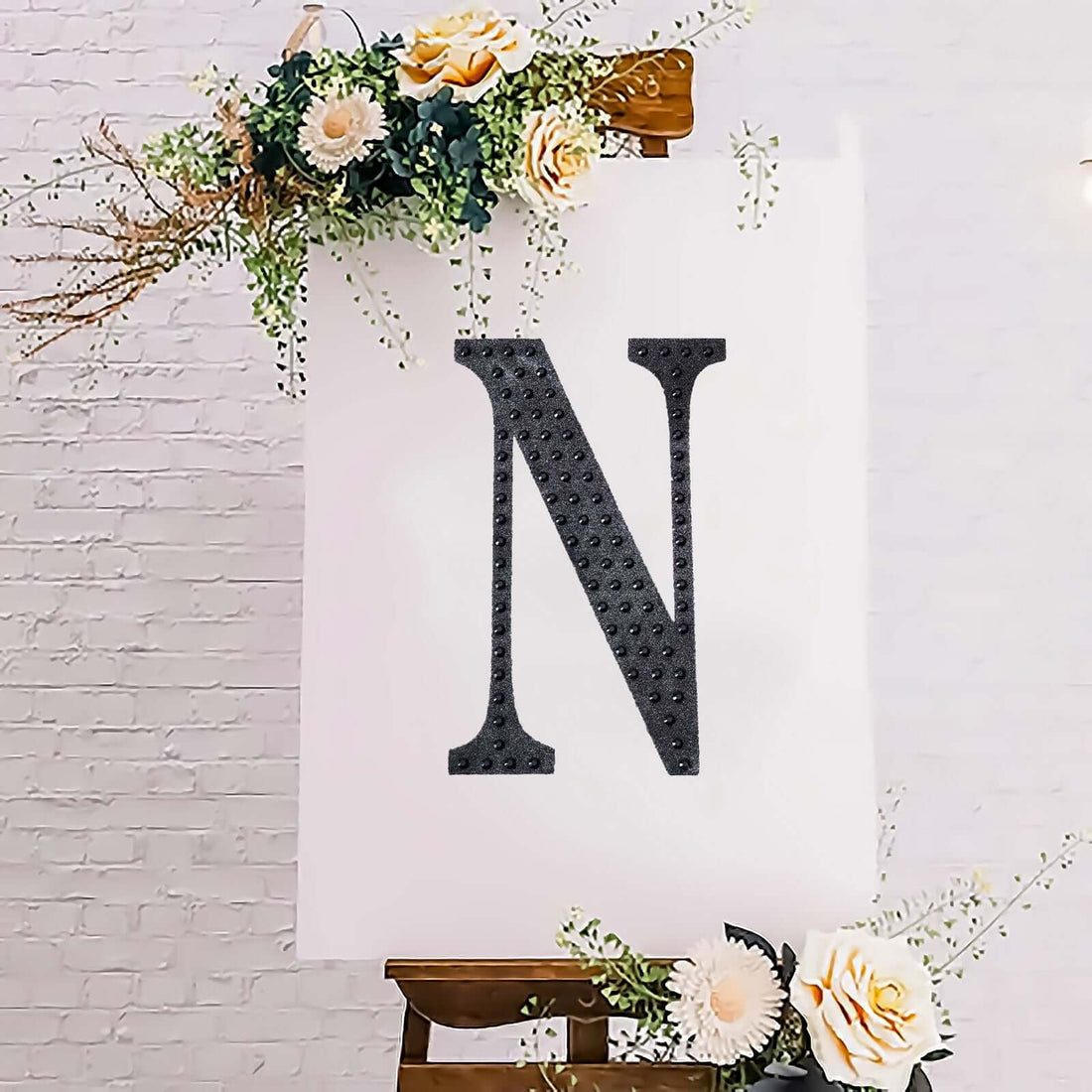 Decorative black letter "N" on a floral backdrop.
