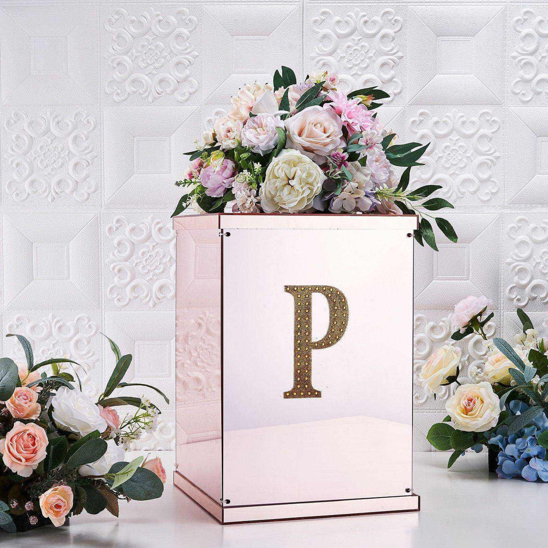 Decorative floral arrangement on a mirrored box with a letter "P" accent.