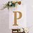 Gold marquee letter "P" on a display with floral accents.