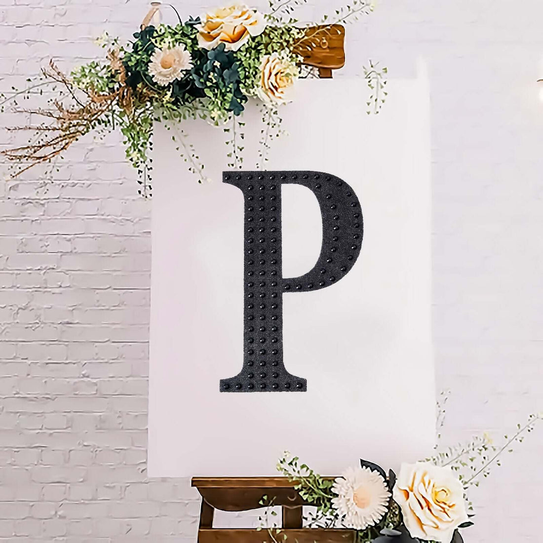 Decorative letter "P" on an easel with floral accents.