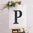 Decorative letter "P" on an easel with floral accents.