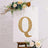Gold rhinestone letter Q on a white poster with floral decorations.