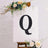 Decorative letter "Q" art on canvas with floral accents.