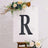 Decorative letter "R" displayed on an easel with floral accents.
