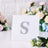 Rhinestone letter S decoration on a white card with floral background.