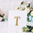 Gold letter "T" decorative piece on a white display background.