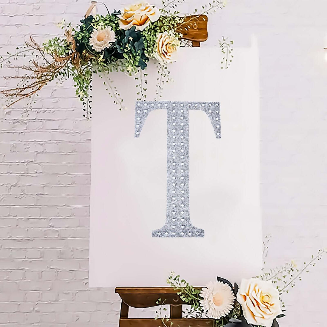 Glittery letter "T" on an easel with floral accents.