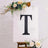 Decorative letter 'T' on an easel with floral accents.