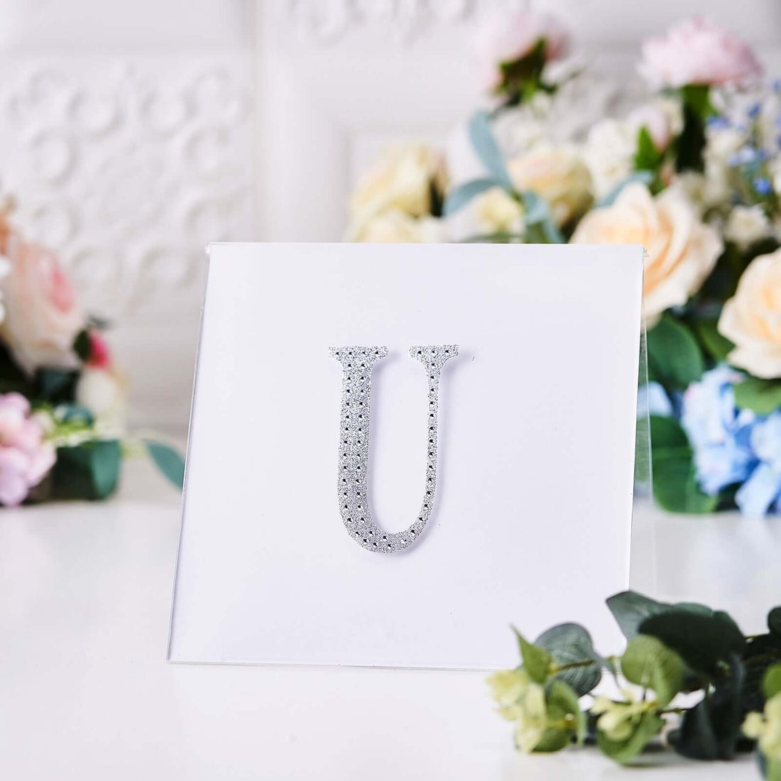 Silver rhinestone letter "U" on a white background.