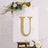 Decorative letter "U" with lights on an easel surrounded by flowers.