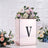 Elegant floral arrangement in a reflective box with a letter "V" on a textured background.