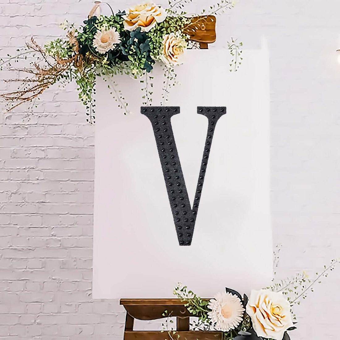 Black letter "V" on a white canvas with floral accents.