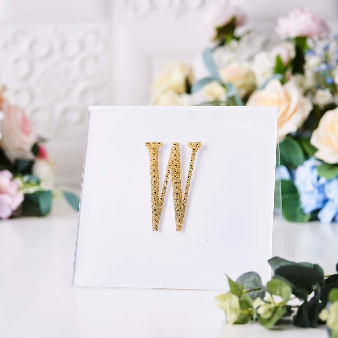 Gold rhinestone letter W on a white card with floral background.