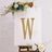 Gold marquee letter "W" on an easel with floral accents.